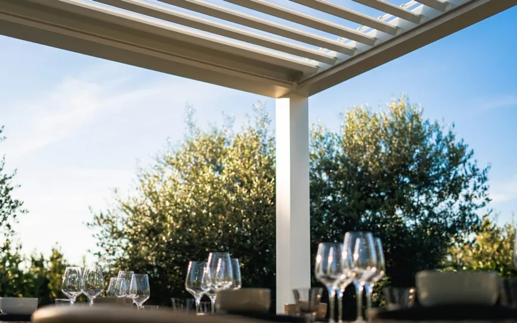 Detaliu lamele deschise parțial — lumină filtrată, perspectivă de sub pergolă